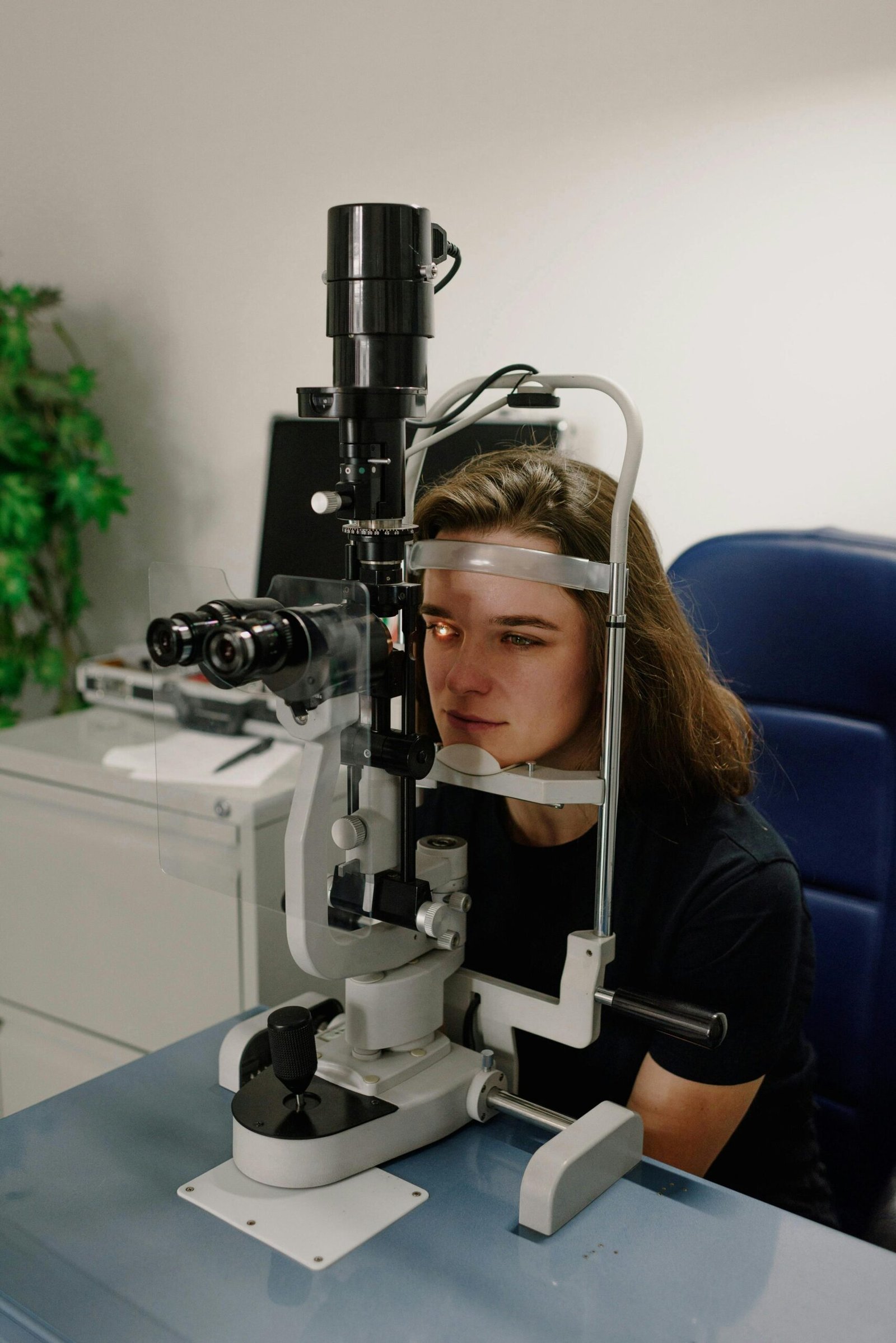 Female patient receiving an eye exam using medical machinery in an ophthalmology clinic.