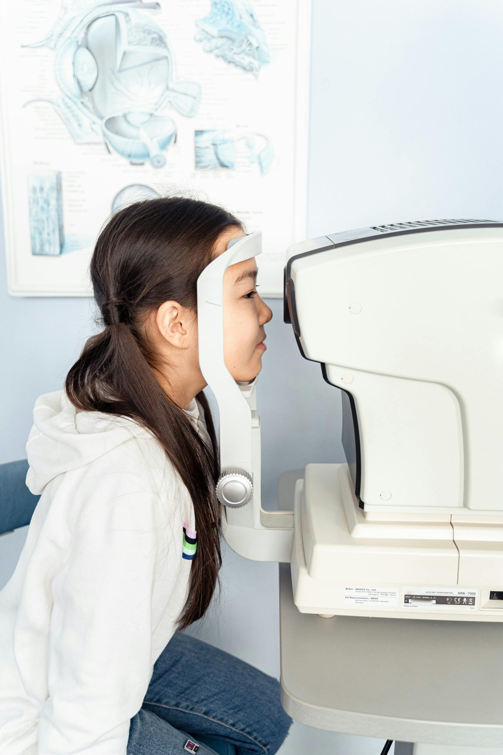 A young girl during an eye examination using an autorefractor in a clinic setting.